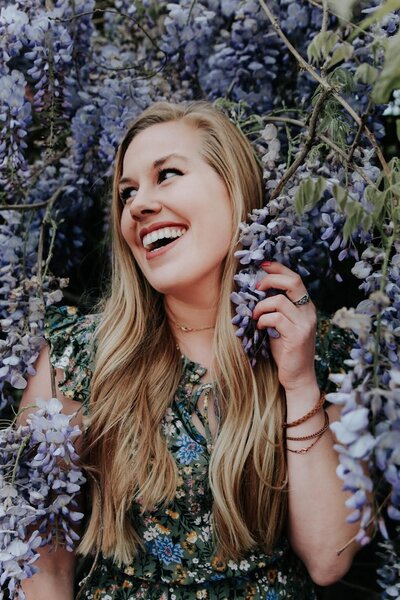 woman smiling while surrounded by purple flowers