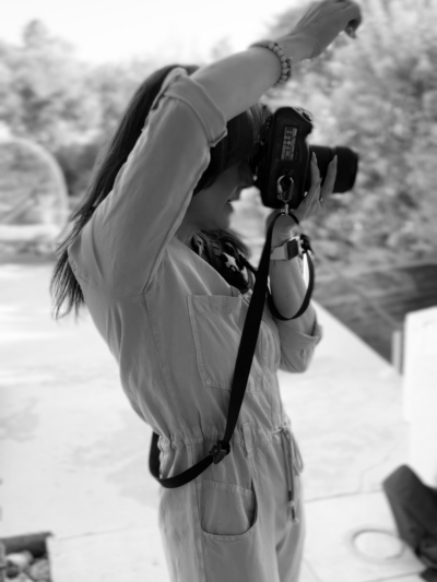 female photographer holding a camera with one hand over her head los angeles