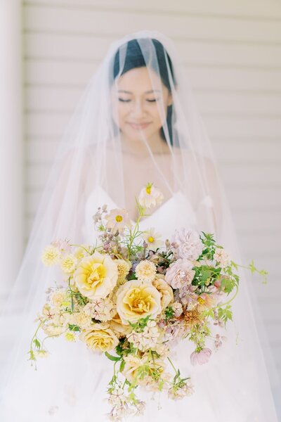Bride under veil with lush spring bouquet