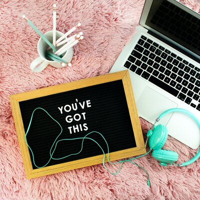 Laptop and black sign saying "you've got this" on pink shag rug