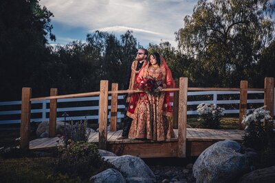 Bride and groom embracing on a bridge in nature at Lake Oak Meadows wedding venue in Temecula.