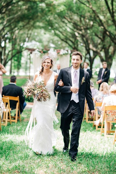 A bride and groom walks down the aisle while Britt Elizabeth captures the precious moments at their outdoor destination wedding.
