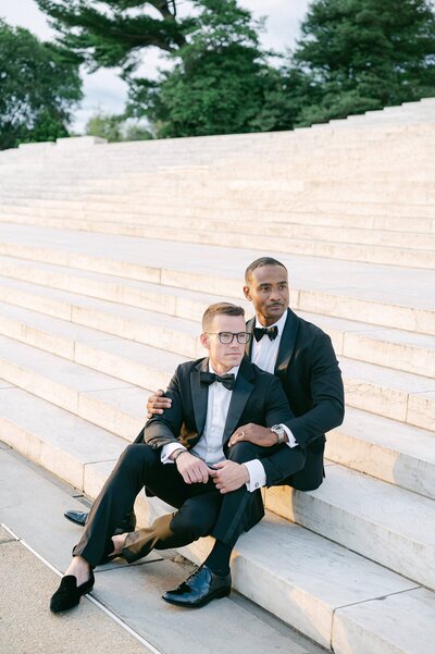 Same sex couple sitting on the steps of the Jefferson Memorial during their engagement session in Washington DC