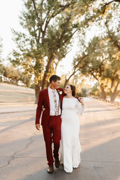 Groom wearing a red suit and floral tie and bride wearing classic long sleeve wedding dress - Alex Bo Photo