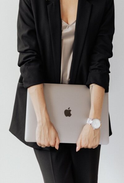 woman in black power suit holding MacBook Pro@2x