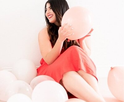 happy woman in a red dress with pink balloons