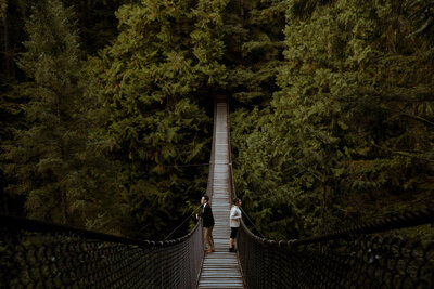 Couple standing on a bridge in a forest at their engagement session