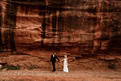 Sedona elopement bride and groom walking in front of red rocks