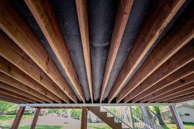 Underneath a deck with wood framing and an EPDM drainage system in between the joists. 