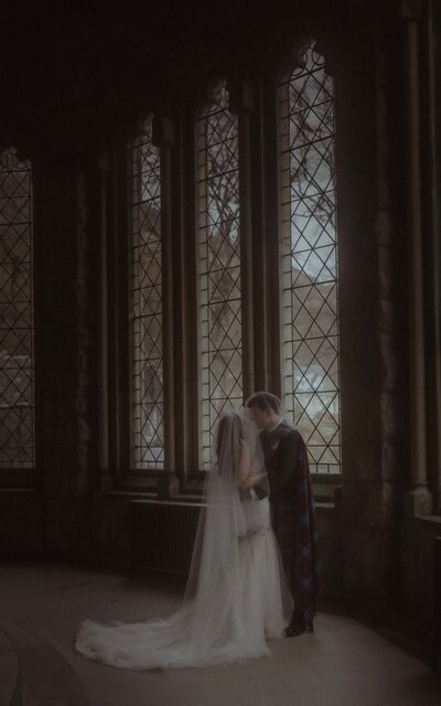Couple sharing a kiss under the veil in St. Kirk, Scotland, captured in a timeless, romantic moment, surrounded by the church's beauty and historic charm
