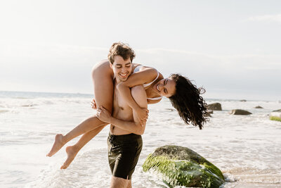 man holds woman on beach