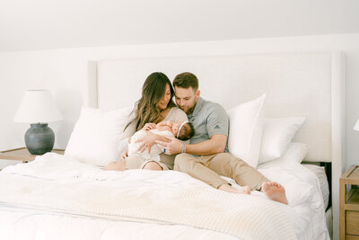 Family of three cuddling in bed during a newborn photoshoot in Arvada Colorado