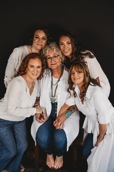 Family Photo of 4 adult daughters and their mom, wearing white shirts and jeans, on black background