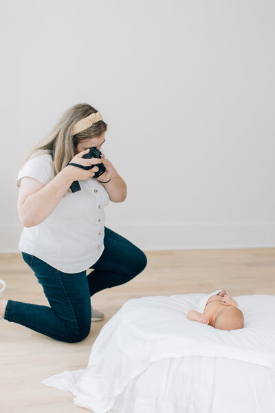 Alpharetta Newborn Photographer taking pictures of baby boy on white bean bag.