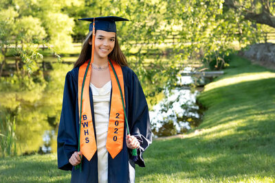 girl in cap and gown holding honor cords