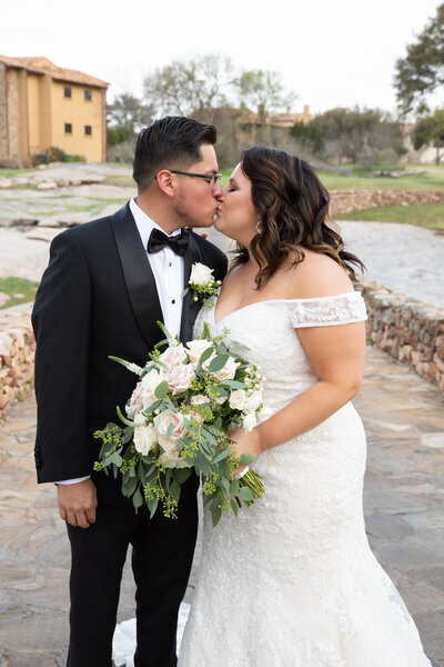 An Austin-based wedding photographer captures the romantic moment of a bride and groom kissing in front of a building.