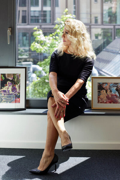 Roxana sitting on the window frame in her office, looking away from camera