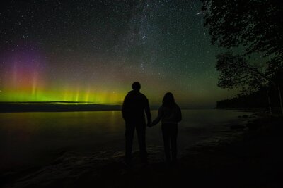 couple holding hands looking at the northern lights