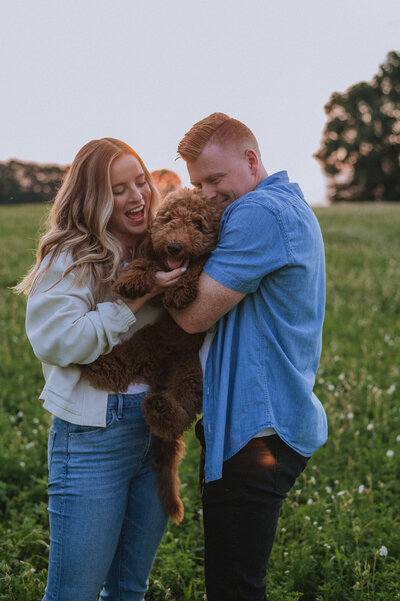 Husband and wife holding  goldendoodle puppy