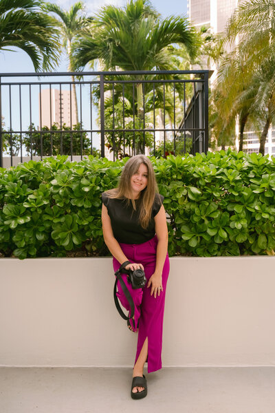 A wedding photographer holds her camera during a branding shoot, embodying her passion for storytelling through both words and images. Her love for deep conversations and attention to detail shine through in her work