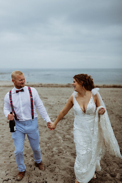 couple share champagne on the beach after wedding