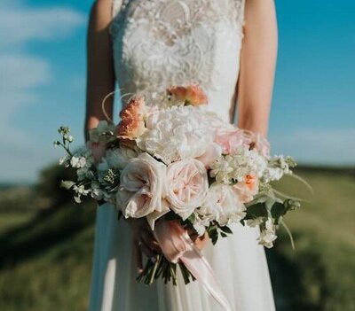 Bride holding peach and white wedding bouquet