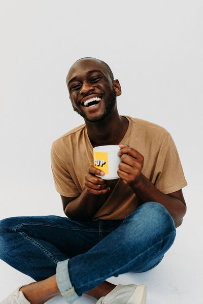 photographer smiling at camera and holding a mug