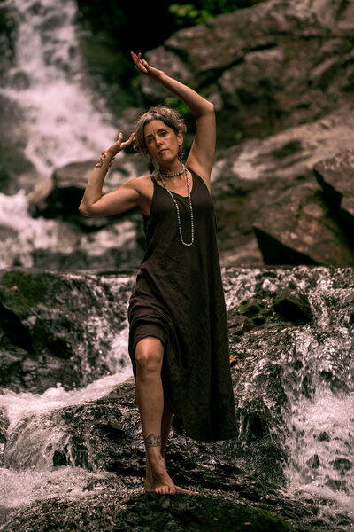 Woman performing embodiment ritual near waterfall