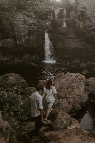 a couple walking to a waterfall during their adventure couples session