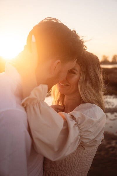 bride and groom on beach with sunset behind them
