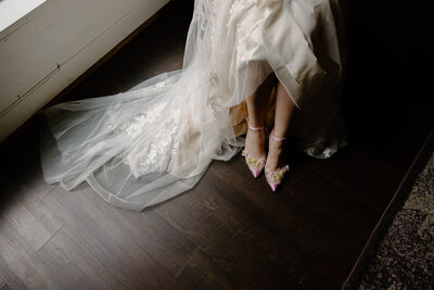 bride shows off her wedding heels in moody lighting
