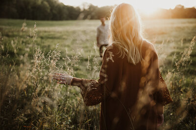 Girl walking toward boy in a whimsical field in the evening sun
