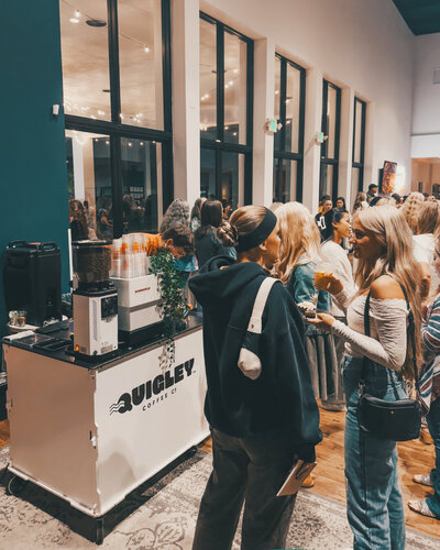 Quigley Coffee Co mobile coffee cart serving drinks at a busy indoor event, showcasing the portable franchise model.