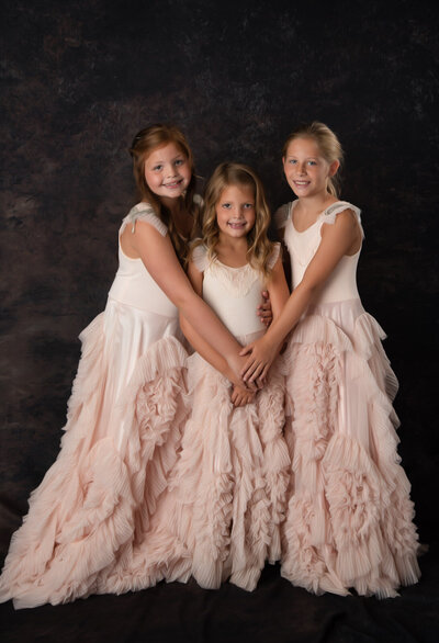 three-sisters-posing-in-studio-with brown-backdrop-in-pink-dollcake-dresses