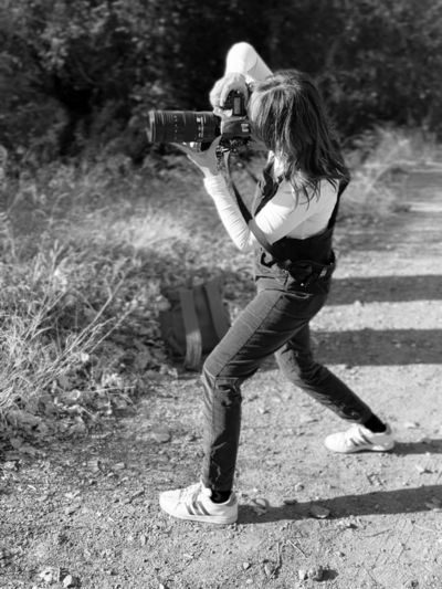 female senior phographer on location holding a nikon professional camera wearing overalls