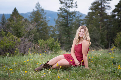 Girl posing for her senior photos in a field with a mountain backdrop in Colorado Springs