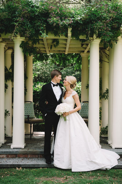 Bride in Amsale Coco Wedding Dress with White Peony Bouquet with Groom in Black Tuxedo  in Charleston Garden