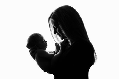 Silhouette of a mother gazing lovingly at her newborn baby.
