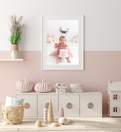 A fine art framed image of a toddler girl hangs on a nursery wall