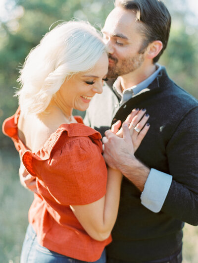 Man kisses woman's forehead while she closes her eyes and smiles during engagement photography session