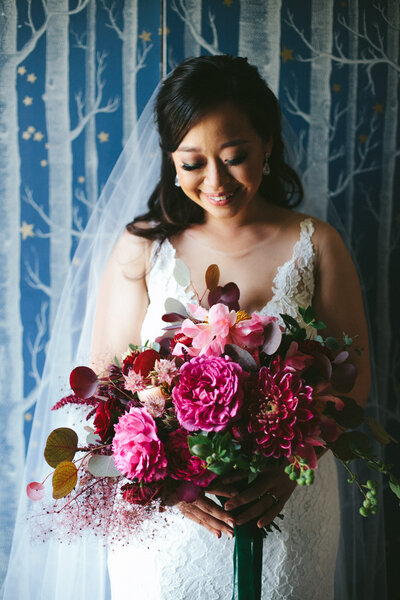 Beautiful bride looks down at her lush pink wedding bouquet