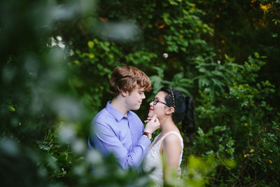 young couple about to kiss while standing partially hidden in the trees taken by San Antonio Photographer Expose The Heart