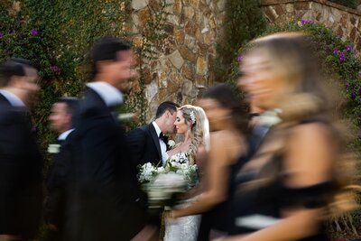 Bride and groom whispering to each other as the crowd around them is blurred out