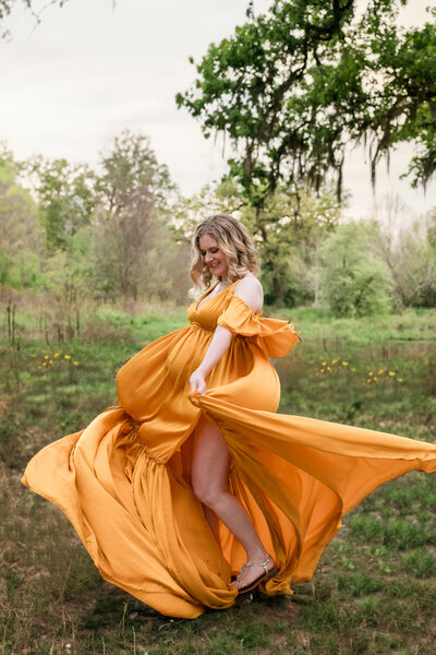pregnant woman twirls in a gorgeous yellow maternity designer gown in Houston, for ally's photography photosession.