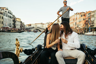 A couple celebrate the proposal on a gondola in Venice Italy with wine glasses