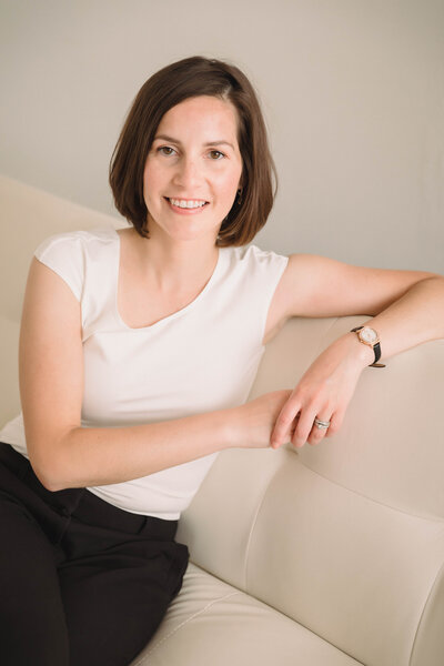Twin Cities Flutist & Teaching Artist Sarah Weisbrod Sitting on a White Couch