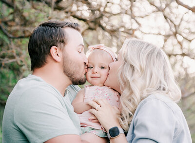 An adorable baby gets kisses from her parents in Yellow Fork Canyon Utah.