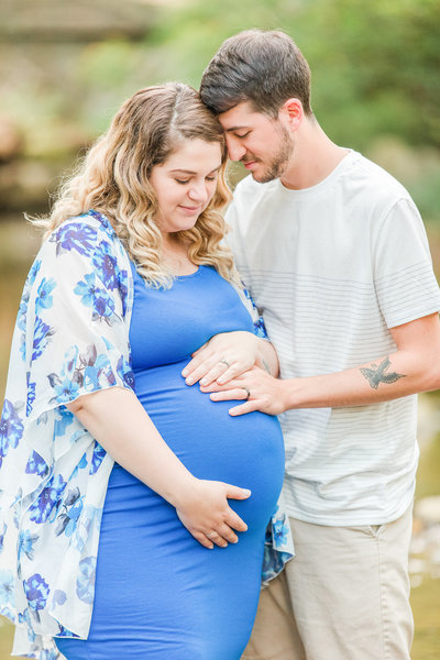 Husband and wife embrace and hold pregnant wife's belly during maternity photoshoot