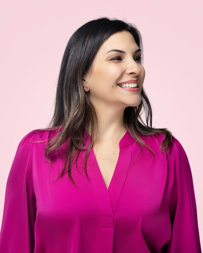 Professional headshot of Rocio with a confident smile and soft natural lighting, photographed on a neutral gray background by Liza Hondros Photography in Fayetteville, NC.