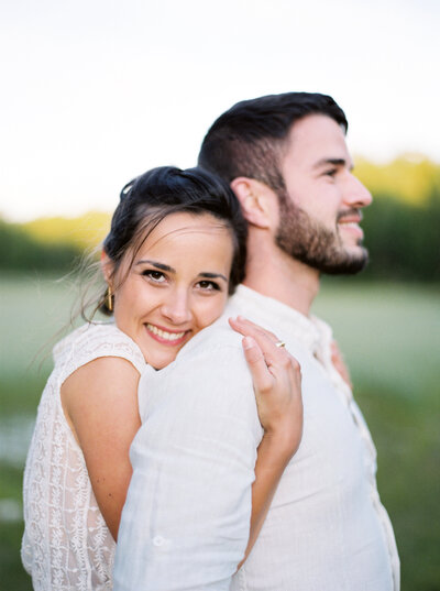 Woman embraces her boyfriend from behind and smiles
